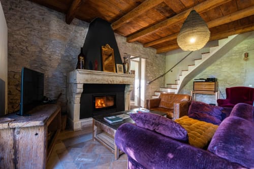Salon chaleureux du Le Mas F B&B à Saint Rémy de Provence avec sièges en velours violet, cheminée et murs en pierre rustique