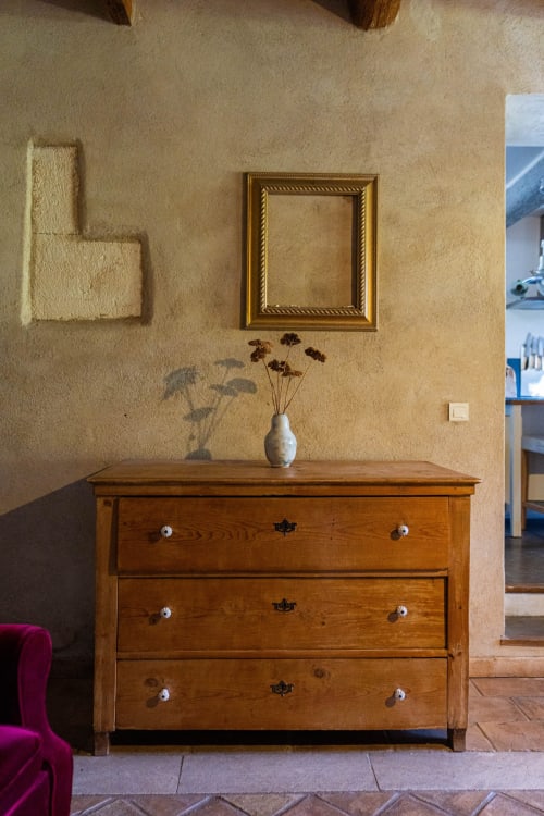 Commode en bois avec vase de fleurs séchées, cadre décoratif et murs texturés au gîte Le Mas F, Saint-Rémy-de-Provence