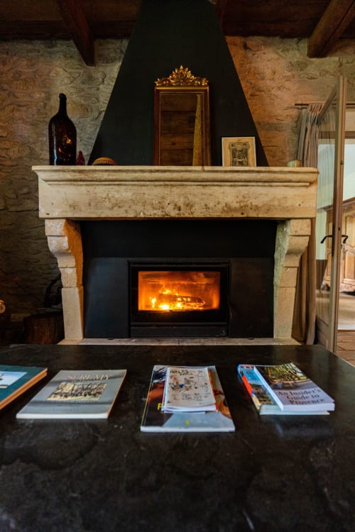 Foyer en pierre avec poêle à bois allumé au Mas F, une maison d'hôtes rustique à Saint-Rémy-de-Provence, France