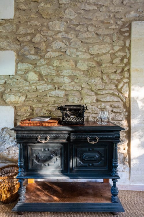 Bureau noir antique avec machine à écrire contre un mur de pierre au Le Mas F, chambre d'hôtes à Saint-Rémy-de-Provence