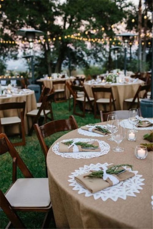 Élégante mise en place de table en plein air au Mas F à Saint-Rémy-de-Provence avec tables rondes, guirlandes lumineuses et serviettes en lin