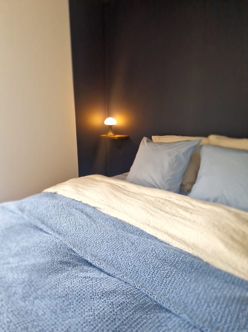 Chambre douillette de la Maison Aurinko à Thénon avec literie bleue, oreillers et lampe de chevet chaleureuse
