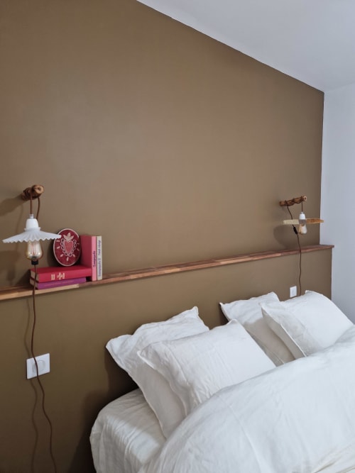 Chambre Maisonaurinko à Thénon avec oreillers blancs, étagère en bois, livres roses et luminaires suspendus