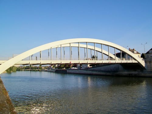 Élégant pont blanc à arches enjambant la rivière à Pont-Sainte-Maxence sous un ciel bleu dégagé avec bâtiments riverains