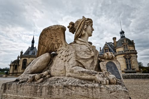 Statue de sphinx ailé au Château de Chantilly près de Pont-Sainte-Maxence avec le château historique en arrière-plan