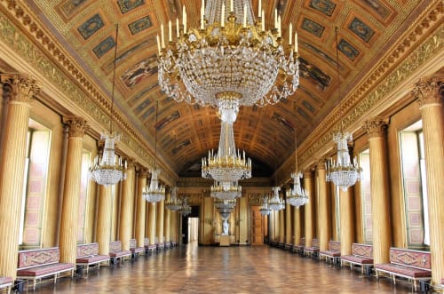 Galerie de palais ornée avec lustres en cristal, colonnes dorées et plafond décoré