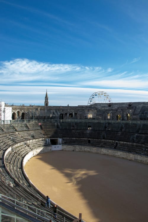 Ancien amphithéâtre romain à Saint-Rémy-de-Provence avec arène de sable et ciel bleu
