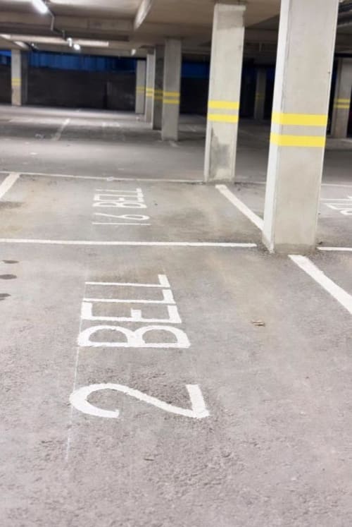 Underground parking garage at Cila Property Manchester with numbered spaces and concrete columns