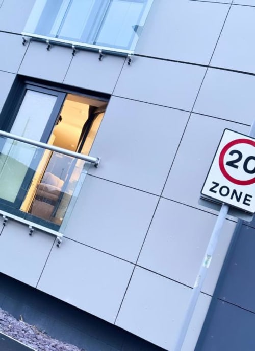 Modern apartment building facade in Manchester with illuminated window and 20 mph zone sign