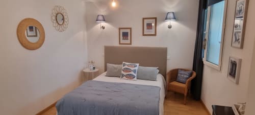 Chambre double élégante avec décoration bord de mer, lit confortable et ambiance chaleureuse. Location saisonnière idéale avec mobilier raffiné, bouilloire et espace détente. Fenêtre ouverte offrant luminosité et vue agréable.