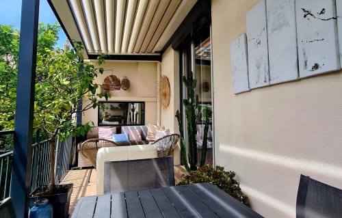 Terrasse moderne et meublée de l'hôtel Le Cocon de Chris à Marseille, avec stores à lames, sièges en rotin et vue sur la verdure