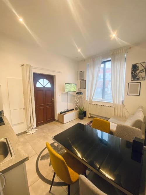 Salon moderne à Illkirch-Graffenstaden avec table noire, chaises jaunes et porte en bois