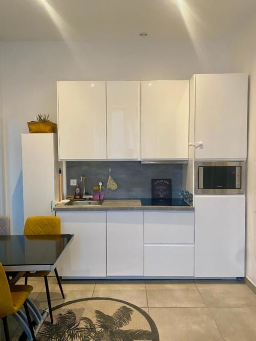 Cuisine moderne blanche avec crédence noire, micro-ondes et design compact dans un studio hôtelier d'Illkirch-Graffenstaden