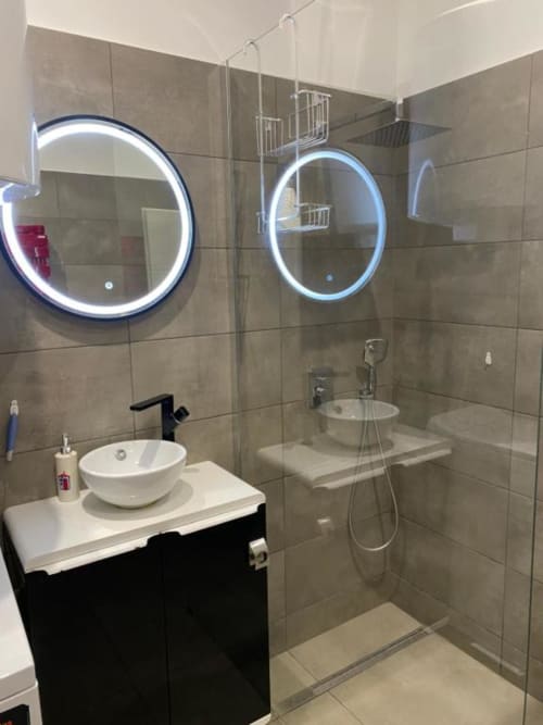 Salle de bain moderne avec miroirs LED, vasque blanche, vanité noire et douche à l'italienne à l'appartement TonyaFlowersapp