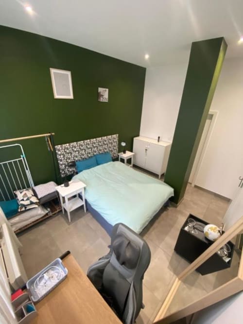 Chambre moderne de l'appartement TonyaFlowersapp à Illkirch-Graffenstaden avec mur d'accent vert et vue sur la ville