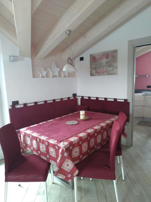 Sala da pranzo moderna dell'hotel Al Dos a Livigno con dettagli bordeaux, tavolo decorato festivo e soffitto con travi in legno