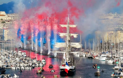 Grand voilier au pavillon français dans le port de Marseille lors des festivités avec feux d'artifice rouges et bleus