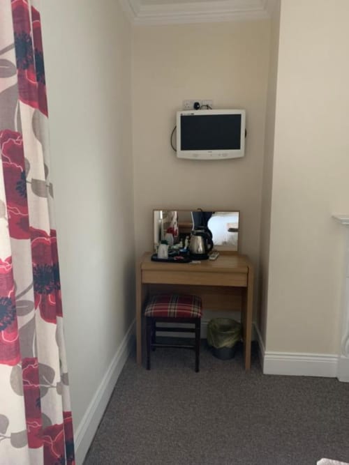 Single bedroom workspace at The Ball Alley B&B showing desk with TV, mirror, chair and storage under beamed ceiling