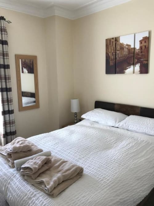 Budget double room at The Ball Alley B&B in Stanley, County Durham with white bedding, dark headboard, wall art, and plaid
