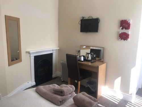 Cozy bedroom at The Ball Alley B&B in Stanley with fireplace, desk, mirror, and floral wall art