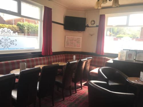 Ball Alley bar area in Stanley, County Durham with red tartan seating, black chairs, TV, and windows overlooking gardens