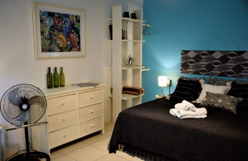 Dormitorio moderno del apartamento LLUNA en Oaxaca con pared turquesa, cama negra, cómoda crema y decoración geométrica