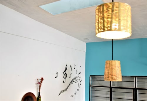 Interior moderno del apartamento LLUNA Oaxaca con pared turquesa, lámparas colgantes de canasta tejida y notas musicales en la pared