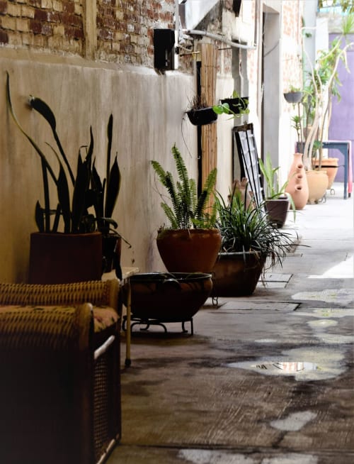 Patio del departamento LLUNA en Oaxaca con plantas en macetas, barandales de madera y muros de piedra rústica