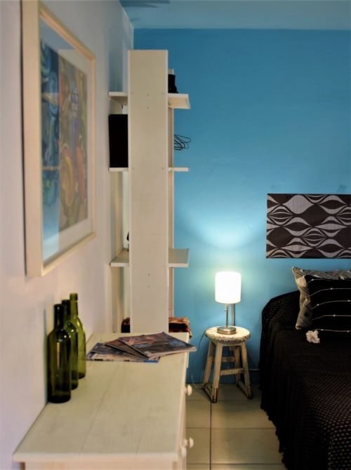 Moderna habitación en apartamento LLUNA Oaxaca con paredes turquesas, estantería blanca, cama y lámpara contemporánea