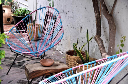 Coloridas sillas tejidas en la terraza del apartamento LLUNA en Oaxaca con plantas en macetas y mesa de madera rústica