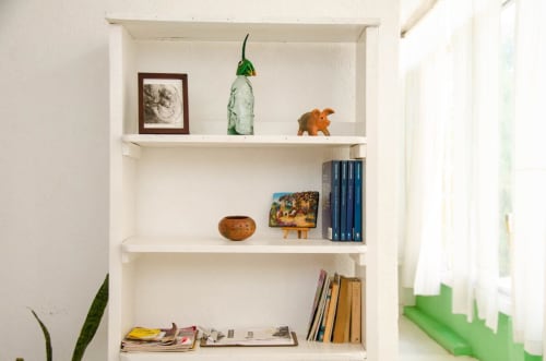 Estantería blanca con objetos decorativos, libros y artículos de estilo oaxaqueño en el apartamento LLUNA, Oaxaca de Juárez