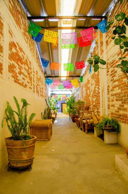 Coloridas decoraciones de papel picado cuelgan en el encantador patio de ladrillo del departamento LLUNA Oaxaca con plantas en macetas