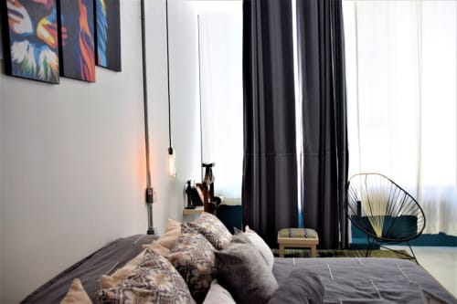 Habitación moderna del apartamento LLUNA en Oaxaca con cama oscura, lámparas colgantes, cortinas negras y silla contemporánea de metal