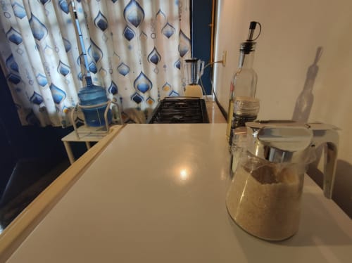 Moderno mostrador de cocina en apartamento LLUNA de Oaxaca con utensilios, cortinas azules estampadas y estufa de gas