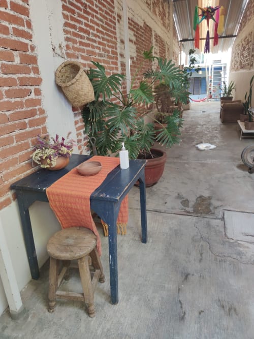 Apartamento LLUNA en Oaxaca con patio rústico: mesa azul, textil naranja, banqueta de madera, plantas en maceta y ladrillo