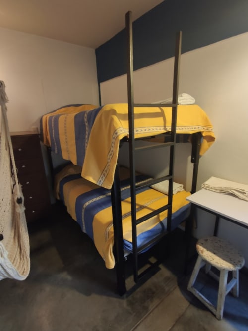 Cama litera de metal negro con ropa de cama amarilla y azul en el apartamento LLUNA, Oaxaca de Juárez
