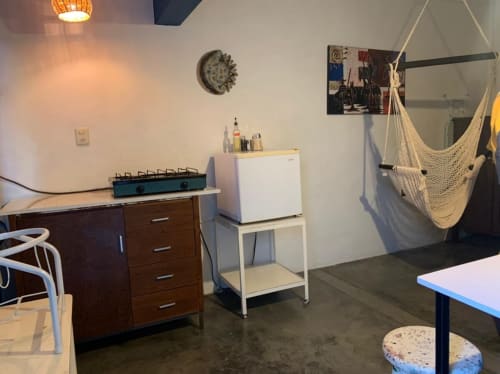 Cocina moderna de apartamento en Oaxaca con muebles de madera, silla hamaca, mesa de comedor y arte decorativo en la pared