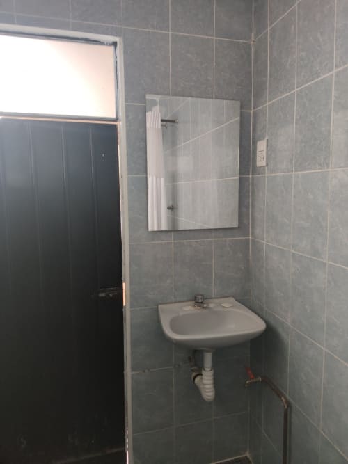 Baño moderno en departamento LLUNA en Oaxaca con azulejos grises, espejo de pared empotrado, lavabo de pedestal y ventana