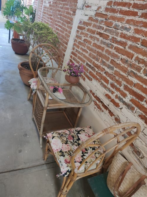 Acogedora zona de descanso en apartamento LLUNA, Oaxaca con sillas de mimbre, flores rosadas y pared de ladrillo