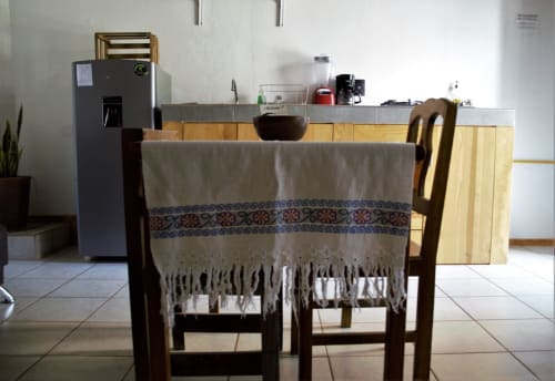 Comedor del departamento LLUNA en Oaxaca con mesa de madera, sillas y mantel decorativo cerca de la cocina