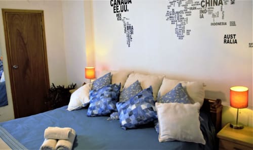 Habitación del apartamento LLUNA en Oaxaca con cama azul, almohadas decorativas, mapamundi en pared e iluminación ambiental
