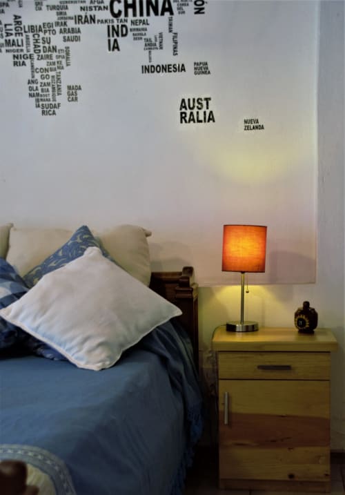 Acogedora habitación del apartamento LLUNA en Oaxaca con mapamundi en la pared, ropa de cama azul, almohadas blancas y lámpara naranja sobre madera