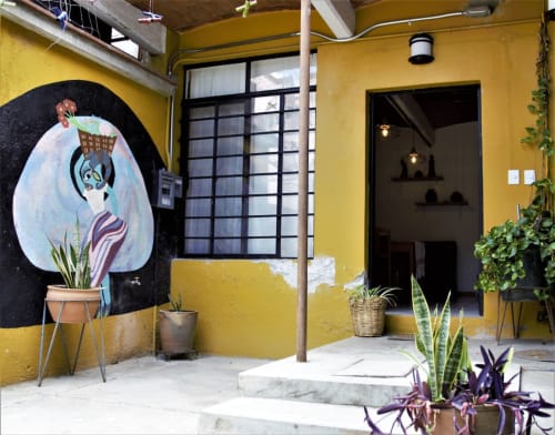 Patio del apartamento LLUNA en Oaxaca con muros amarillo vibrante, arte mural, plantas en macetas y arquitectura colonial