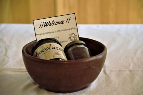 Canasta de bienvenida con artículos de chocolate en bowl de madera en apartamento LLUNA, Oaxaca