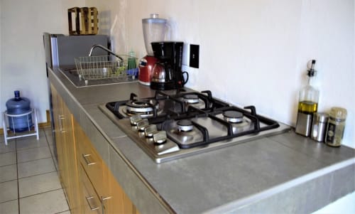 Cocina moderna en apartamento LLUNA, Oaxaca, con estufa de gas, cafetera y encimera gris