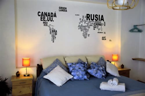 Habitación del apartamento LLUNA en Oaxaca con ropa de cama azul, vinilos de mapamundi y iluminación cálida