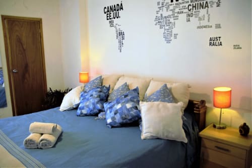 Dormitorio moderno en apartamento LLUNA, Oaxaca: almohadas azules, cama beige, mapa mundi y iluminación ambiental
