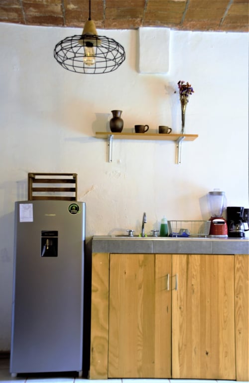 Cocina moderna del apartamento LLUNA en Oaxaca con electrodomésticos de acero inoxidable, muebles de madera e iluminación colgante