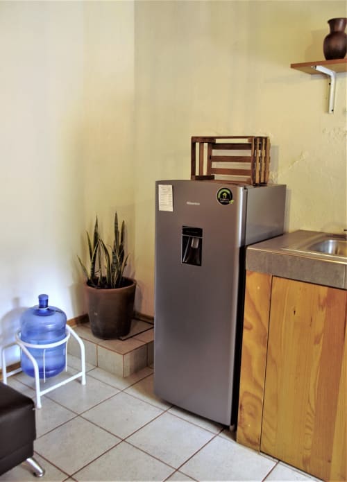 Cocina americana del Hotel LLUNA en Oaxaca con refrigerador, gabinetes de madera y planta en maceta