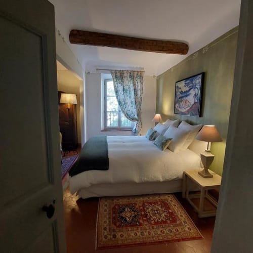 Chambre douillette à La Cordeline B&B à Brignoles avec literie blanche, murs verts, poutre en bois et vue sur la ville